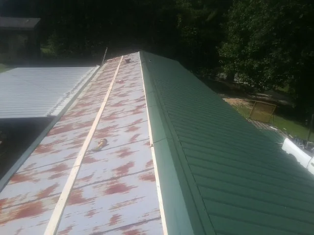 Old rusted panels beside newly installed green metal roofing — Wind Damage Roof Repair by Roofing Brothers in Brainerd