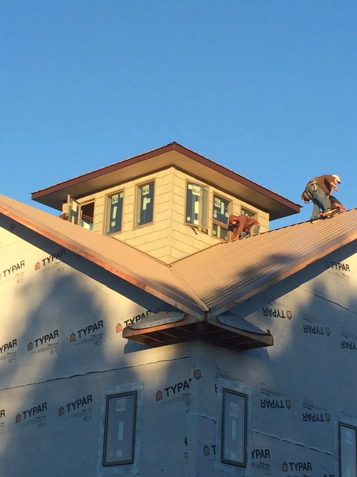 Roofers working around a rooftop cupola on a new metal roof at sunset — Roof Waterproofing in Brainerd by Roofing Brothers